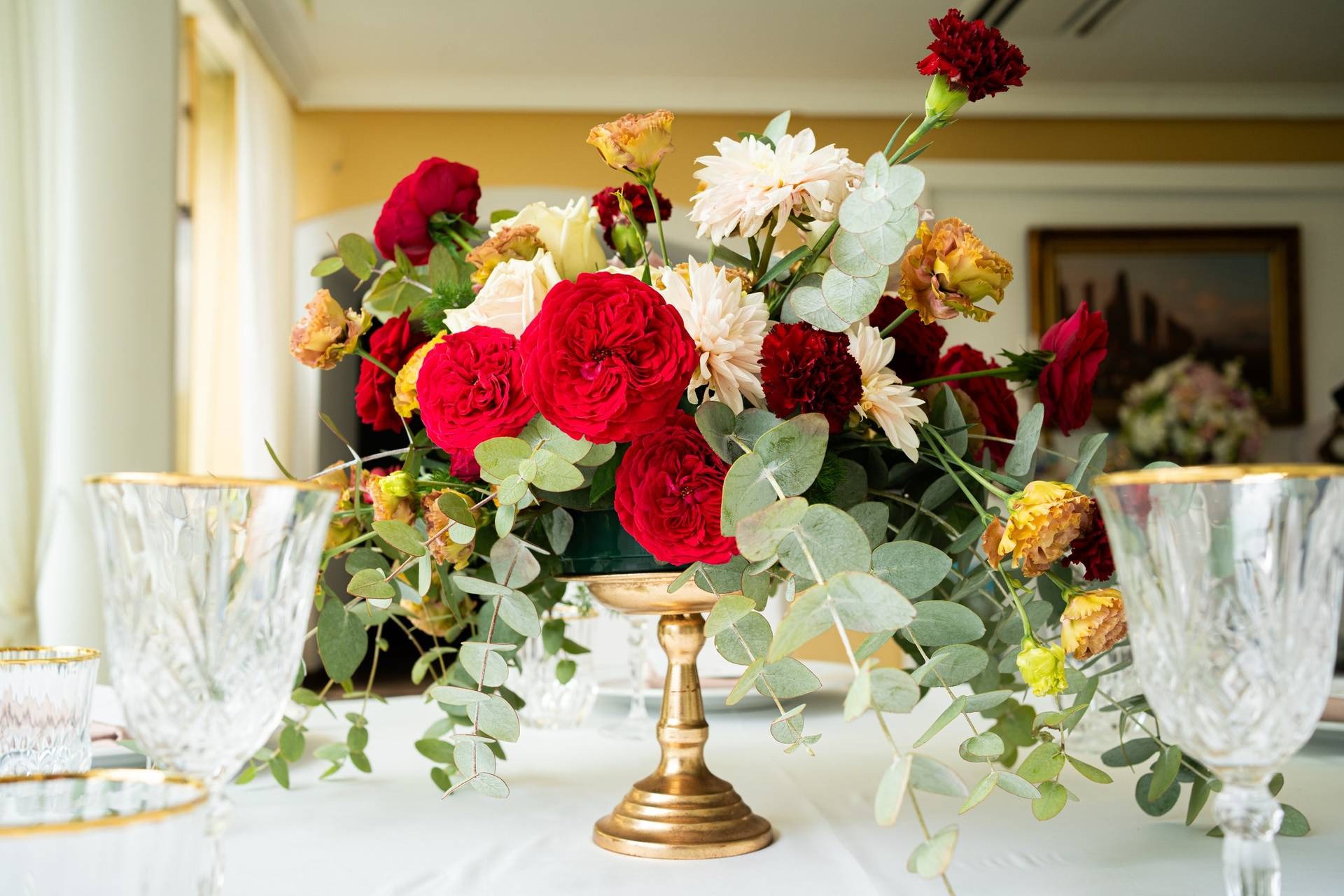 Centrotavola con alzatina in ottone, rose rosse ed eucalipto
