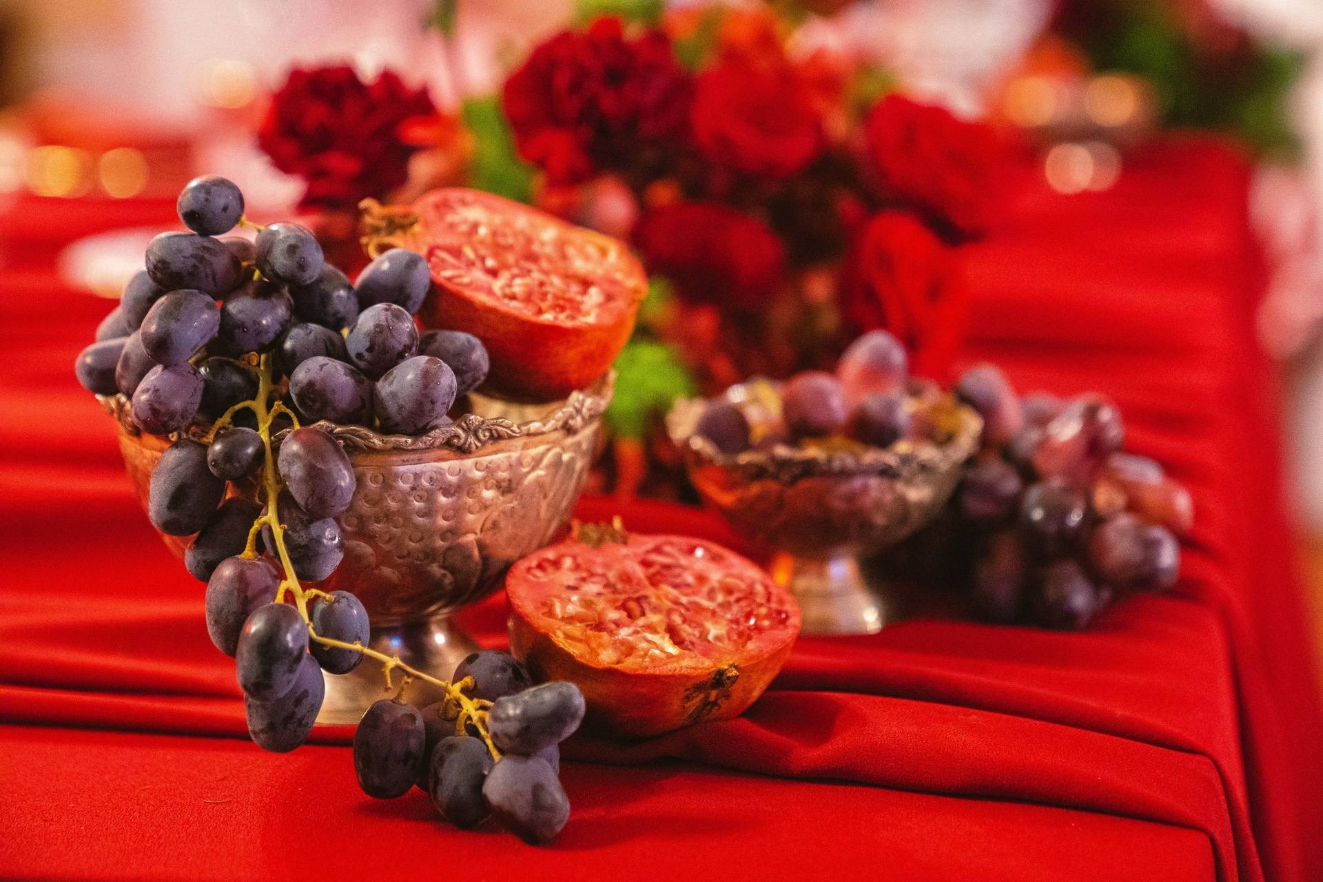 Dettaglio frutta autunnale con uva e melagrana su tovaglia rossa