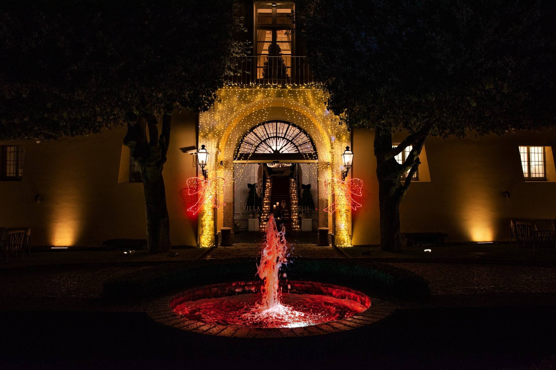 Facciata notturna con luminarie natalizie e fontana illuminata
