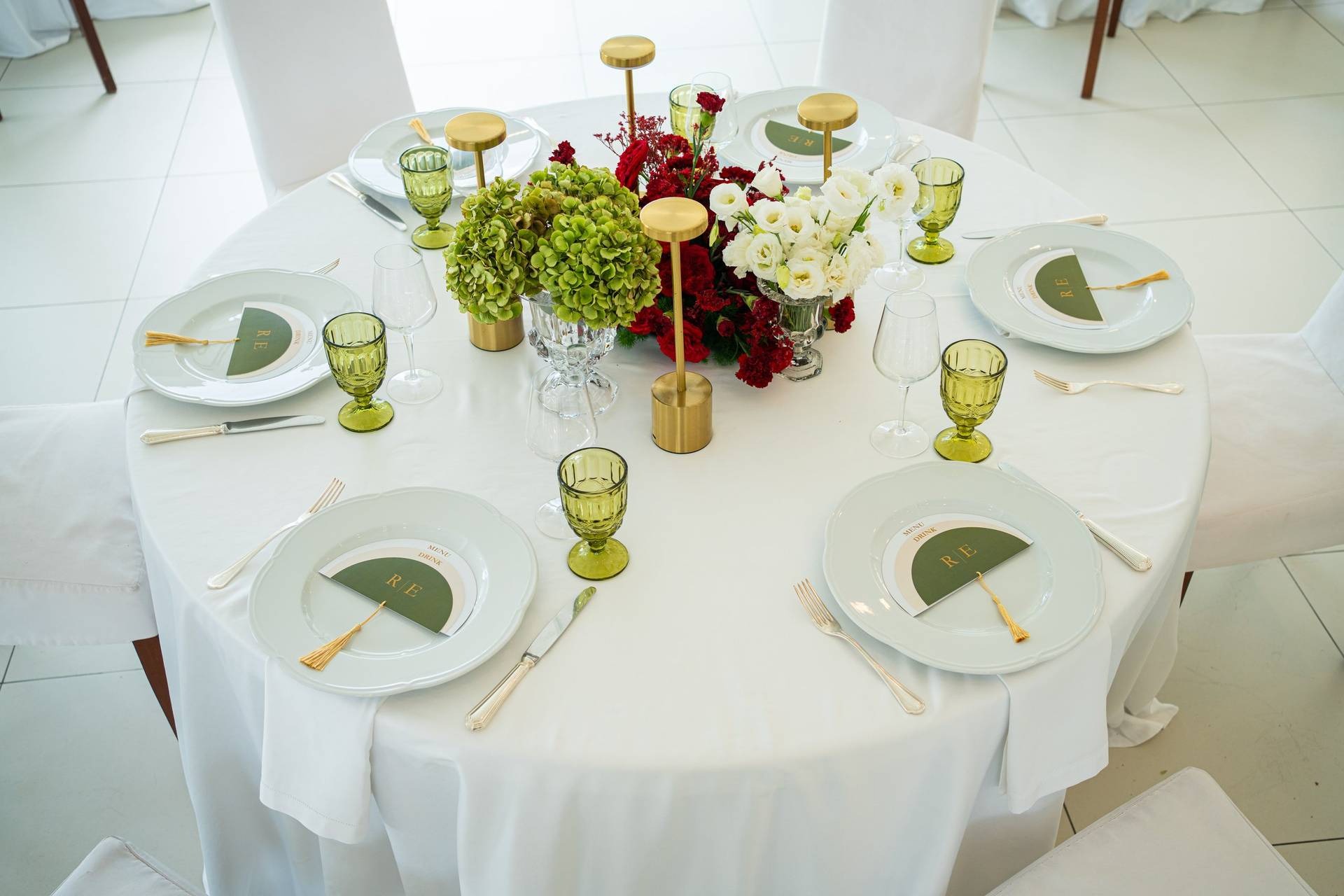 Mise en place tavolo bianco con menu verde e lampade oro